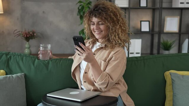 One woman with curly hair at home use mobile phone smartphone texting