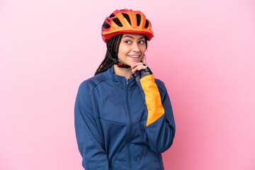 Teenager cyclist girl isolated on pink background thinking an idea while looking up - obrazy, fototapety, plakaty
