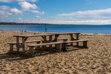 Fototapeta na wymiar Picnic benches on the beach in Avon Beach, Mudeford, Dorset, England, UK
