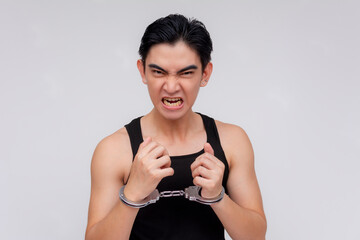 A defiant young man in handcuffs cursing and shouting after being arrested. Isolated on a white...