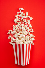 Popcorn in red and white striped paper box isolated on red  background