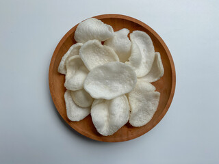 Kerupuk bawang putih, crackers made from tapioca flour and garlic, on wooden plated, isolated on white background
