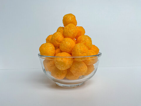 Cheese balls crackers in a transparent bowl, isolated on white background