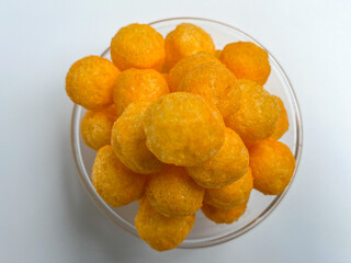 Cheese balls crackers in a transparent bowl, isolated on white background, dlat lay or top view