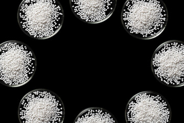 Many laboratory Petri dishes with samples of white polymer plastic granules.
