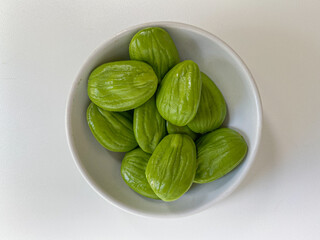 Parkia speciosa, the bitter bean, petai, or pete. Uncooked peeled seeds after peeled, in a bowl. Isolated on white background