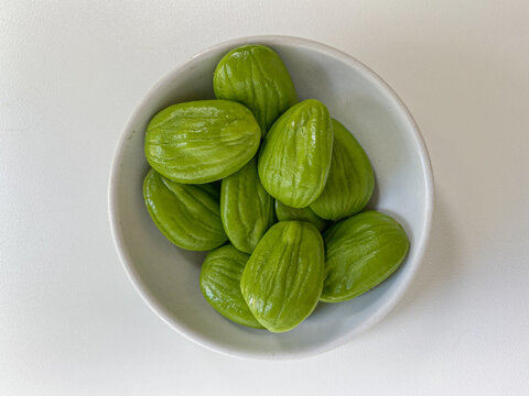 Parkia speciosa, the bitter bean, petai, or pete. Uncooked peeled seeds after peeled, in a bowl. Isolated on white background