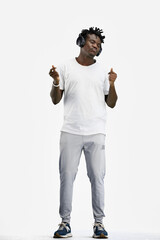 A man, full-length, on a white background, listening to music with headphones
