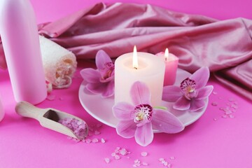 Spa still life with orchid flowers and candles on pink background, relaxation atmosphere, body care 