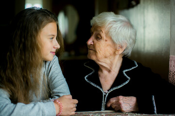 The girl and her great-grandmother, looking at each other. - 722068666