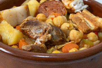 A clay bowl with an Andalusian chickpea stew, isolated on a white background, close-up. Spanish food concept.