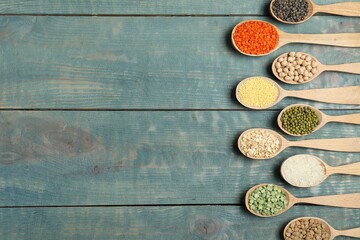 Flat lay composition with different types of legumes and cereals on blue wooden table, space for...