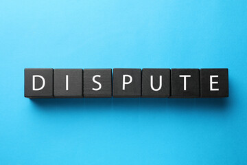 Word Dispute made with black cubes on light blue background, top view