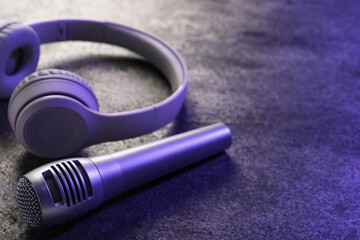 Microphone and headphones on grey textured table, closeup with space for text. Sound recording and reinforcement