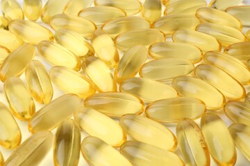 Many yellow vitamin capsules on white background, closeup