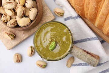 Tasty pistachio cream and nuts on light table, flat lay