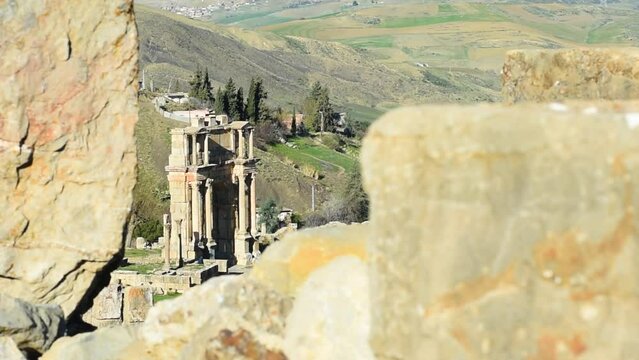 High-angle footage of tourists walking through the Arch of Caracalla in the ancient Roman town of Djemila. Setif, Algeria. UNESCO World Heritage Site.