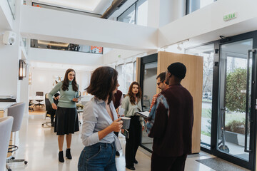 Multiracial group of business coworkers engaging in a casual office meeting while standing.