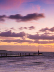 Obraz premium Tranquil Sunset Over Ocean Pier With Vibrant Skies And Calm Waters