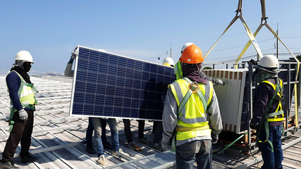 The Photovoltaic solar panels transported  by the Crane trucks and workers at the rooftop of a...