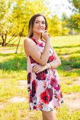 Fototapeta premium A beautiful slender girl in a bright elegant dress walks in a summer park. Slender girl.