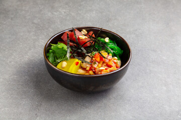 Poke with tuna, beans, vegetables in a plate gray background
