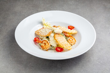 Caesar salad with shrimp in a plate gray background