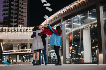 Joyful friends tossing paper airplanes on a city street with festive lights at night.
