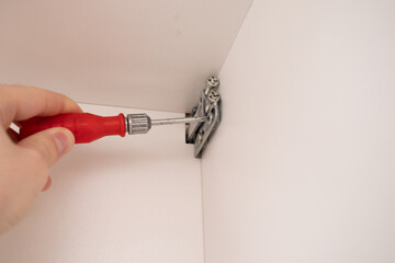 hands of a worker installing a Fasteners for kitchen drawers to the wall.