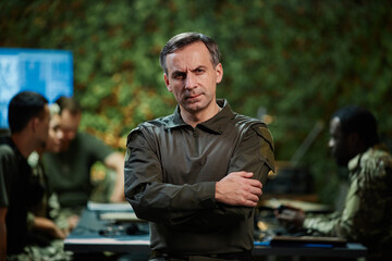 Confident mature male security officer crossing his arms by chest and looking at camera while...