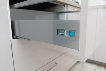 Installing wooden drawer on sliding skids in contemporary cupboard cabinet.