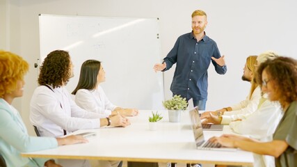 Man leading a meeting in a coworking using a board
