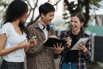 Diversity, college student focusing on laptop work or reading while other classmates in the background, outdoor portrait on campus campus.