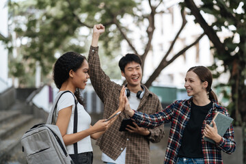 Happy group of college students use laptop feel excited overjoyed triumph with good news