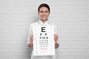 Ophthalmologist with vision test chart near white brick wall