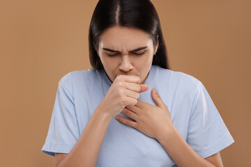 Woman coughing on brown background. Cold symptoms