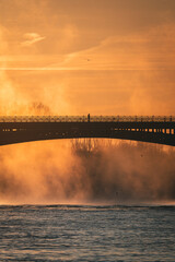 Mann auf Brücke bei Sonnenaufgang über Fluss