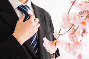 スーツ男性と桜で新入社員のイメージ