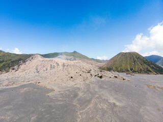 Aerial view of a vast volcanic landscape with ash-covered ground and craters.