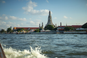 Obraz premium A scenic view of the wat arun temple from across the river under a clear blue sky.