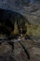 A person exploring a dimly lit cave, taking photographs of the surroundings.