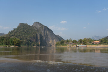 Serene riverside landscape with a mountain backdrop and clear blue skies.