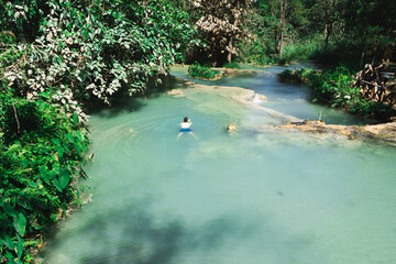 People swimming in a serene, natural forest pool