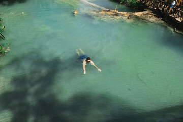 Person enjoying a serene swim in a clear blue river