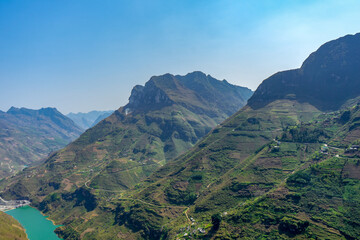 A panoramic view of a mountain range with terraced slopes beside a winding river.