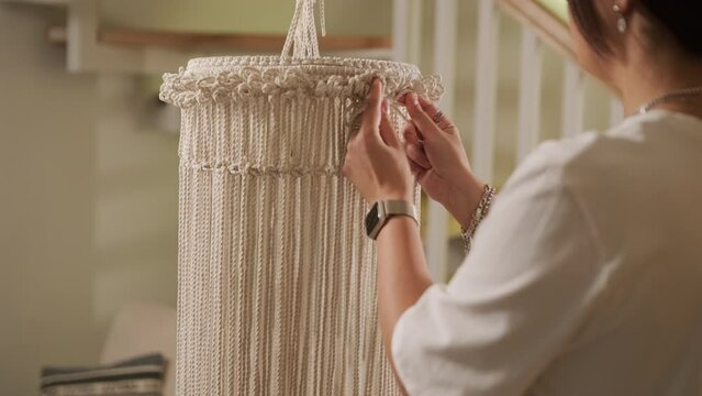 Home hobby, knitting macrame. Women's hands knit an ornament with thick threads.