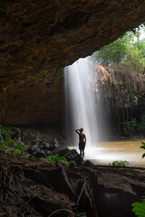 A person standing mesmerized by a stunning, secluded waterfall inside a cave