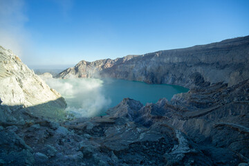 Misty morning view of a tranquil volcanic crater lake with rugged terrain.