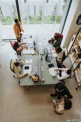 An enthusiastic diverse team of coworkers collaborating in an innovative indoor office, discussing...