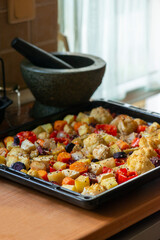 Close up image of a delicious and healthy looking tray with roasted colourful root vegetables fresh from the oven in a sunlit kitchen